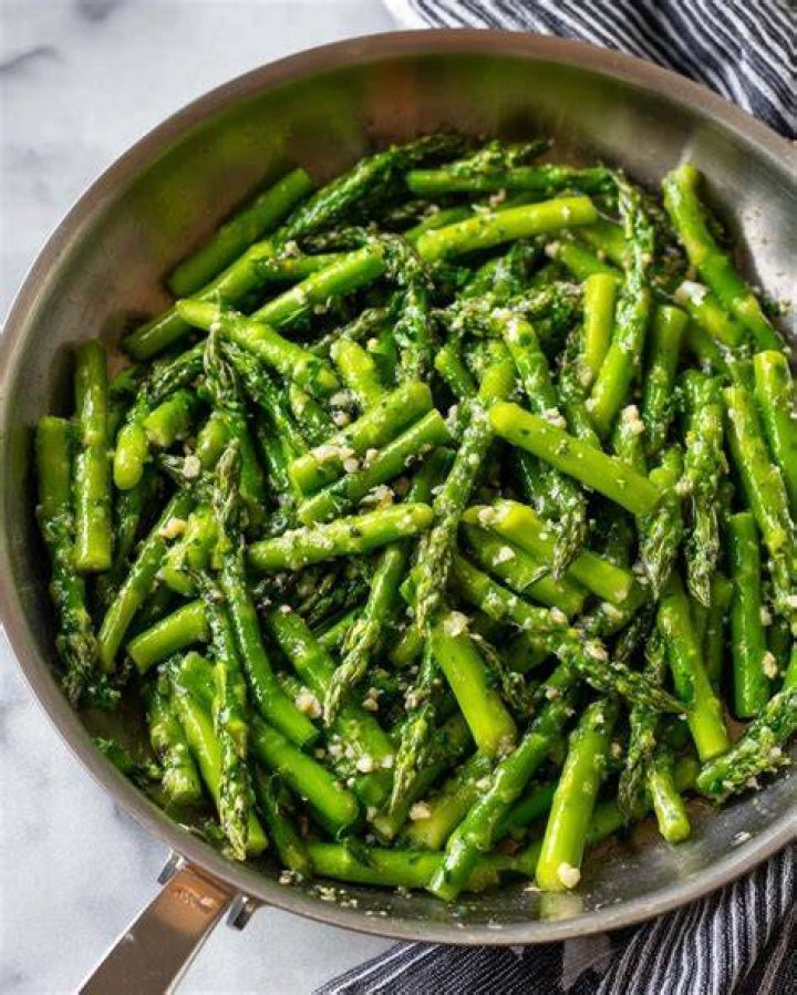 Asparagus, herbs, peas, and garlic on a wood board.