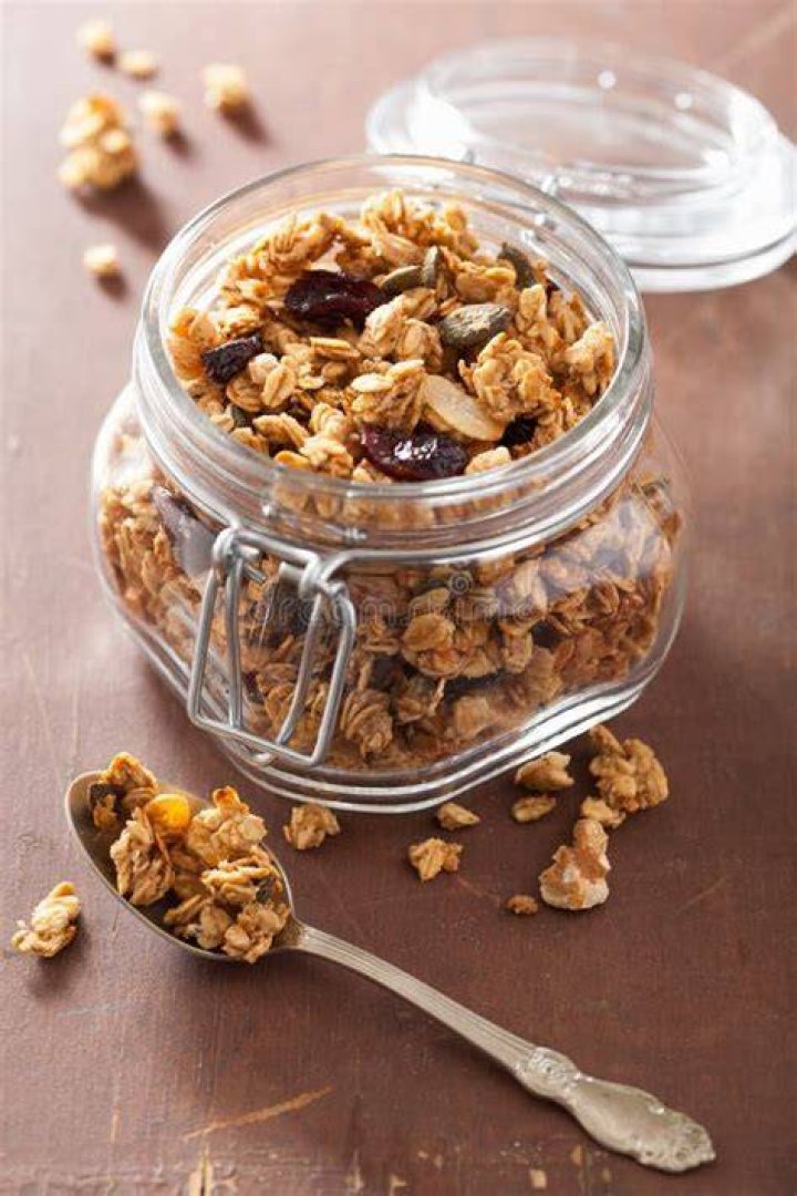 Granola in a glass jar on a wooden board.