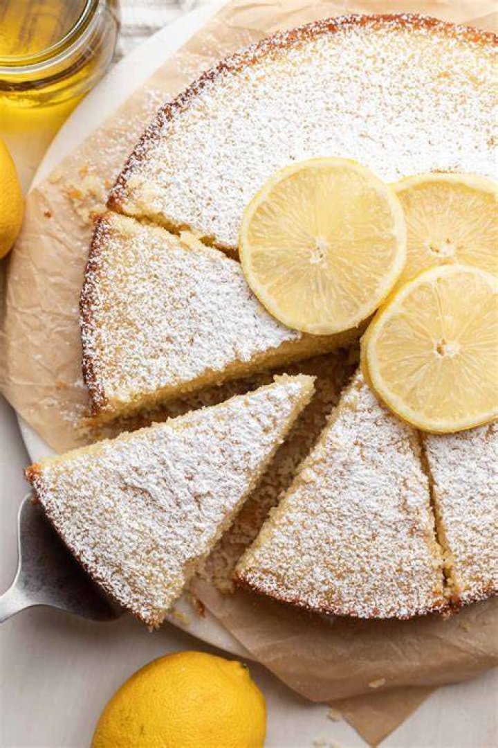 Lemon olive oil cake topped with white icing on a metal rack.