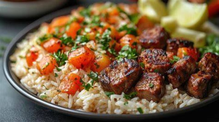 Plate of rice with grilled vegetables and sausage.