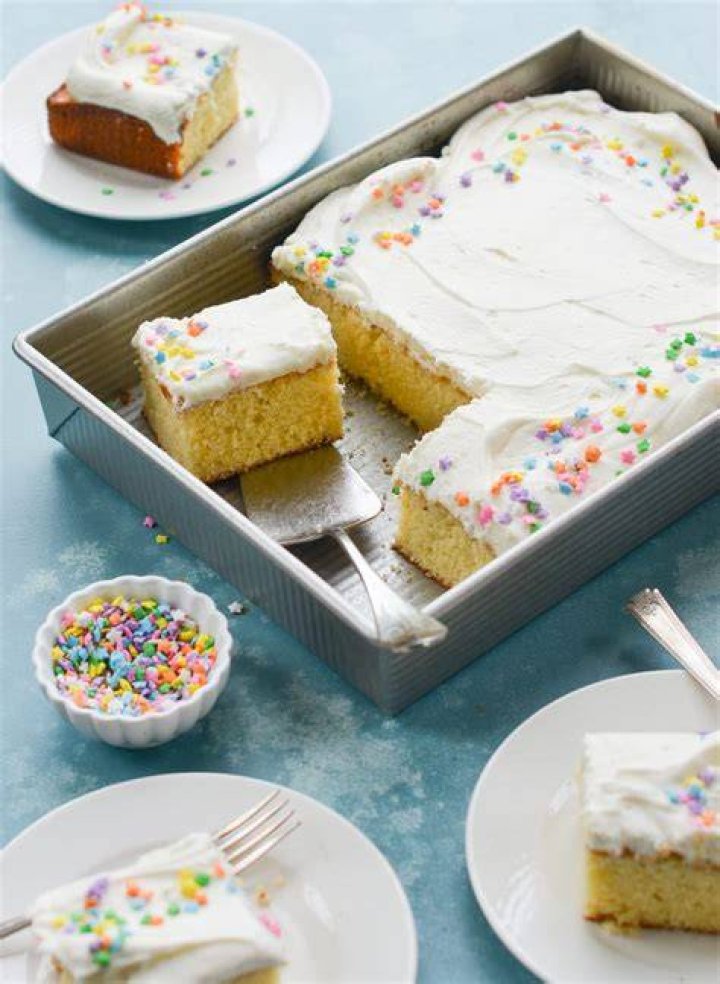 Vanilla sheet cake topped with vanilla frosting and sprinkles.