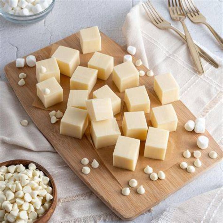 White chocolate fudge topped with pecans in a yellow box.